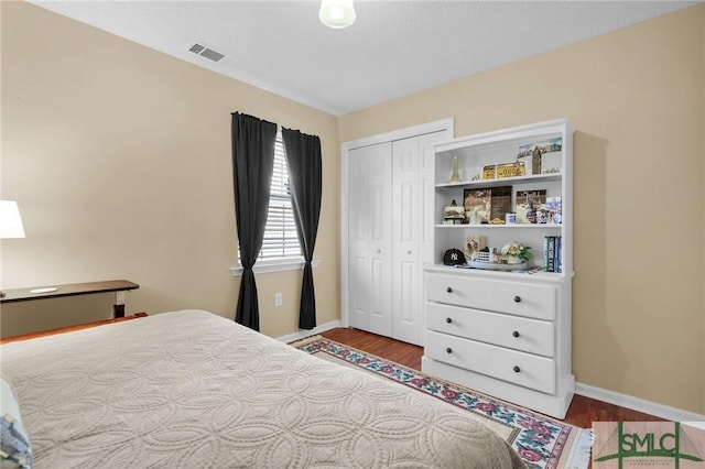 bedroom with baseboards, visible vents, and wood finished floors