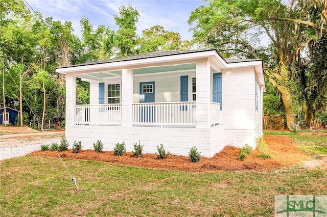 bungalow-style home featuring concrete block siding, covered porch, and a front yard