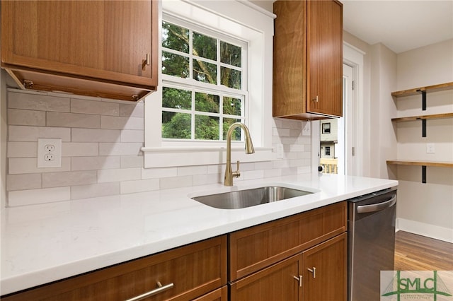 kitchen with wood finished floors, dishwasher, light countertops, a sink, and backsplash