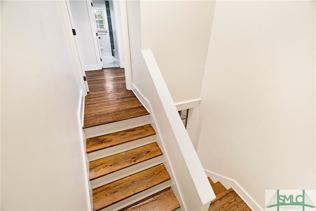 staircase featuring baseboards and wood finished floors