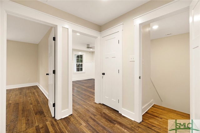 corridor with baseboards and dark wood-type flooring