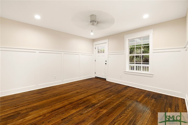 unfurnished room with wainscoting, a decorative wall, a ceiling fan, recessed lighting, and dark wood-type flooring