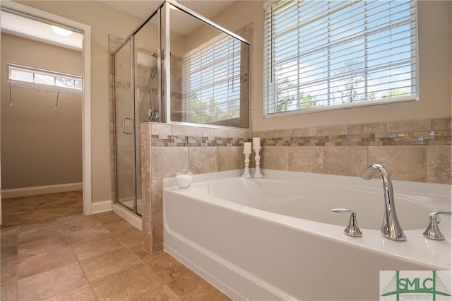 full bathroom featuring a walk in closet, a stall shower, and a garden tub