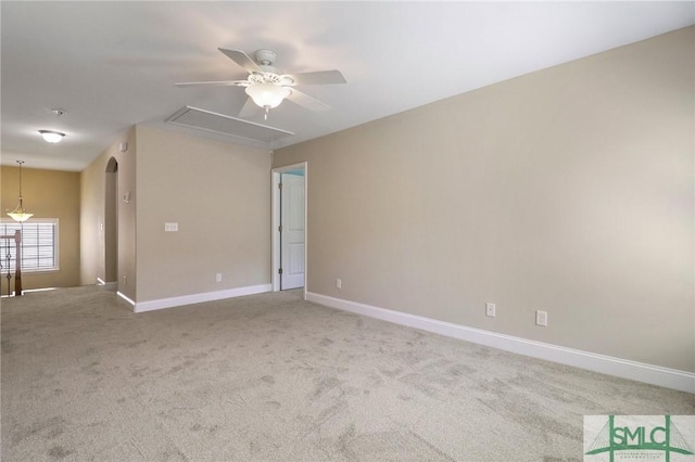 carpeted spare room with a ceiling fan, baseboards, and attic access
