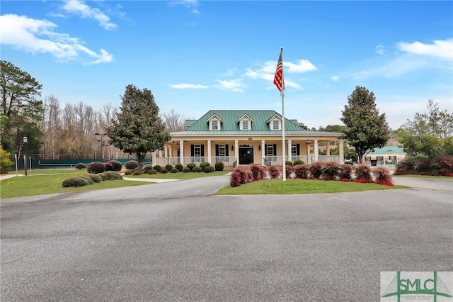 view of front of property featuring a porch, fence, metal roof, and a standing seam roof