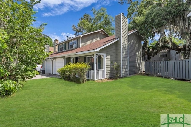 rear view of property with a lawn, an attached garage, fence, and a chimney