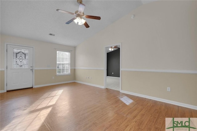 interior space featuring baseboards, ceiling fan, light wood finished floors, and lofted ceiling