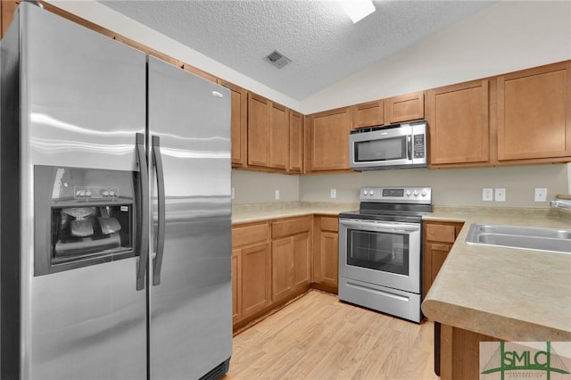 kitchen with visible vents, appliances with stainless steel finishes, a sink, light countertops, and light wood-style flooring