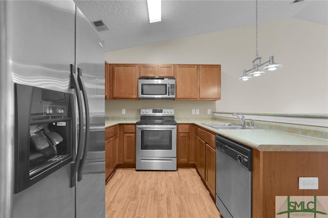 kitchen with visible vents, a sink, vaulted ceiling, and stainless steel appliances