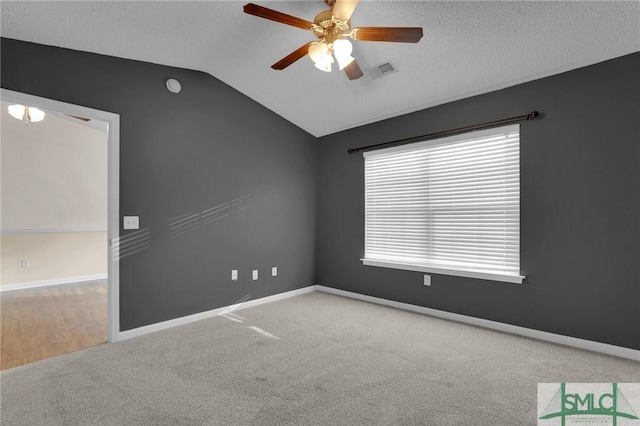 carpeted empty room featuring visible vents, baseboards, ceiling fan, and lofted ceiling