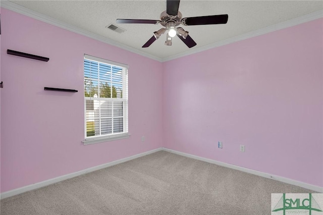 carpeted spare room with visible vents, ornamental molding, baseboards, and a ceiling fan
