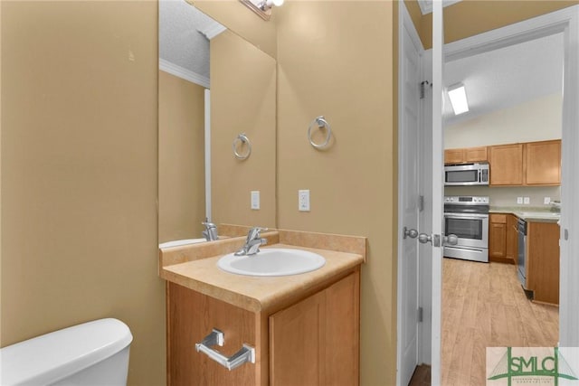 half bathroom with vanity, toilet, wood finished floors, lofted ceiling, and ornamental molding