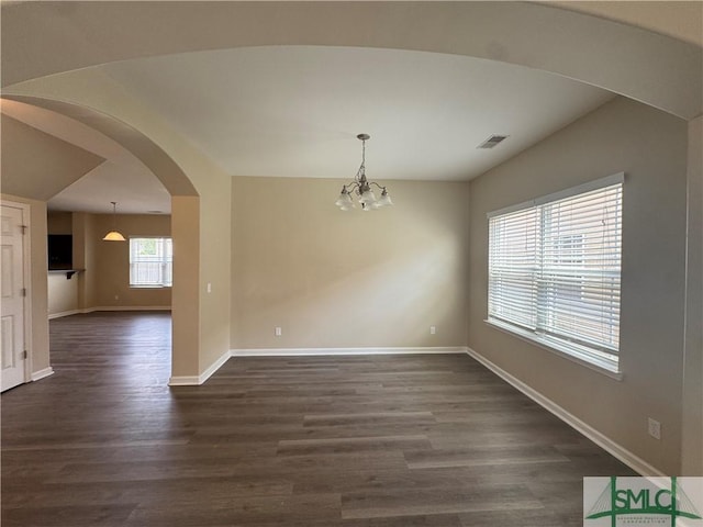 unfurnished dining area featuring visible vents, arched walkways, baseboards, a notable chandelier, and dark wood-type flooring