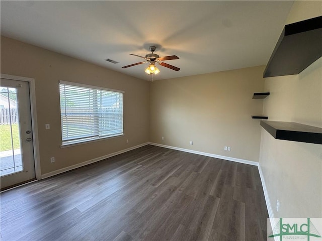unfurnished living room featuring visible vents, dark wood-type flooring, baseboards, and ceiling fan