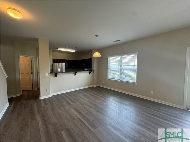 unfurnished living room featuring baseboards, dark wood-style floors, and visible vents
