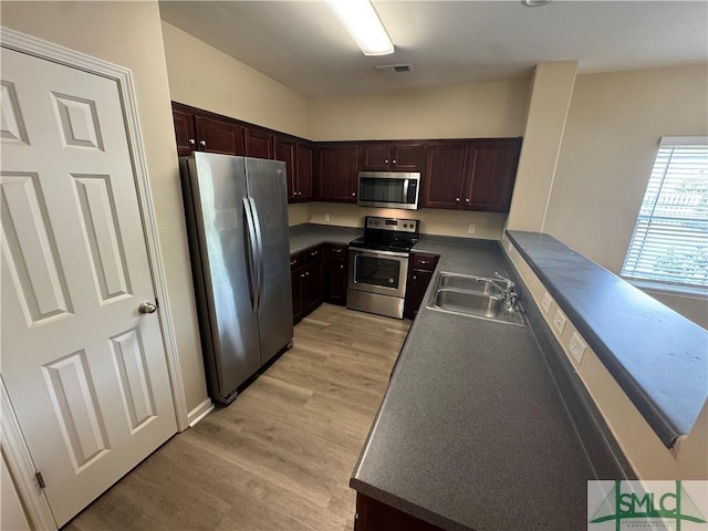 kitchen with visible vents, dark brown cabinets, a sink, stainless steel appliances, and light wood-style flooring