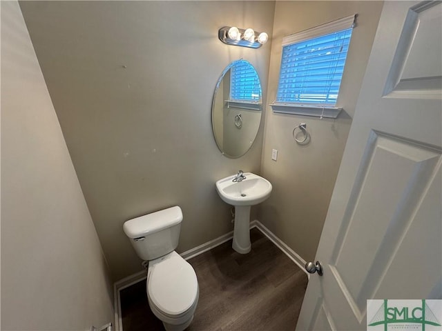half bath featuring toilet, baseboards, and wood finished floors