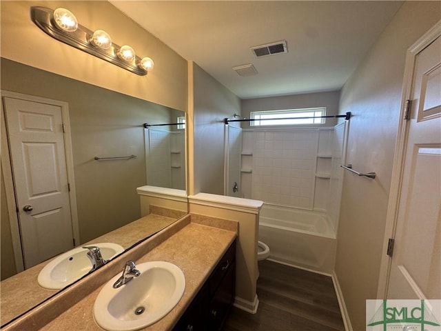 bathroom with visible vents, vanity, wood finished floors, toilet, and bathtub / shower combination