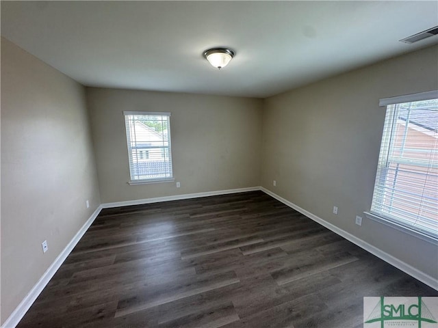 empty room with baseboards, dark wood finished floors, and visible vents
