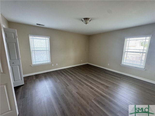 empty room with baseboards, dark wood finished floors, and a wealth of natural light