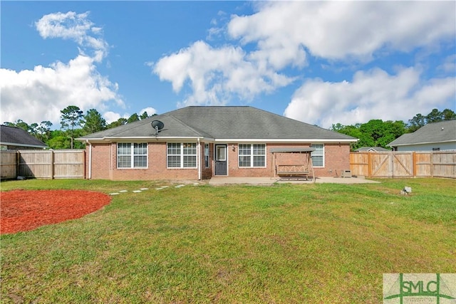 rear view of house with a lawn, a gate, a patio area, brick siding, and a fenced backyard
