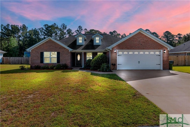 traditional-style home featuring a garage, fence, brick siding, a lawn, and driveway