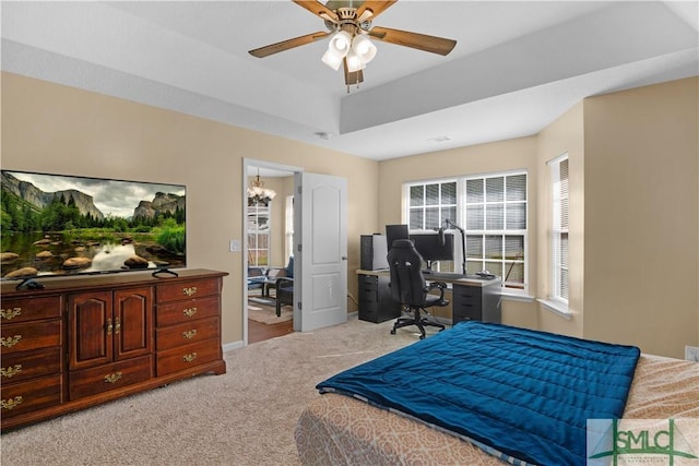 carpeted bedroom featuring a tray ceiling, baseboards, and a ceiling fan