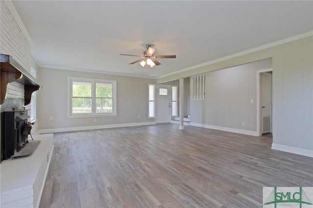 unfurnished living room featuring crown molding, ceiling fan, wood finished floors, and a wood stove