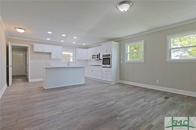 kitchen with ornamental molding, baseboards, a center island, white cabinetry, and appliances with stainless steel finishes