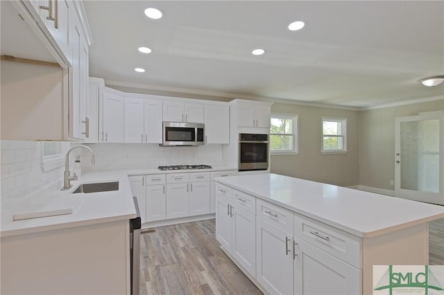 kitchen featuring crown molding, a sink, appliances with stainless steel finishes, and tasteful backsplash