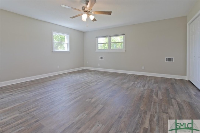 empty room featuring a ceiling fan, baseboards, dark wood finished floors, and visible vents