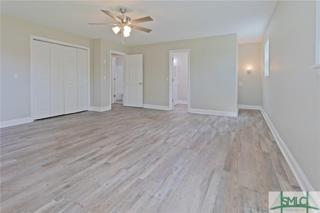 unfurnished bedroom featuring a closet, light wood-style flooring, ceiling fan, and baseboards