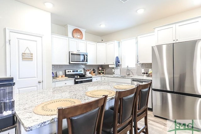 166 Benelli Dr, Pooler, GA 31322 - kitchen featuring light stone countertops, a breakfast bar, white cabinetry, a sink, and stainless steel appliances