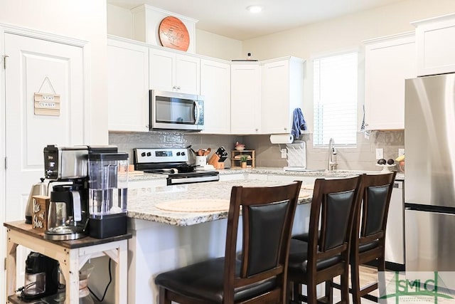 166 Benelli Dr, Pooler, GA 31322 - kitchen featuring white cabinets, appliances with stainless steel finishes, tasteful backsplash, and a kitchen bar