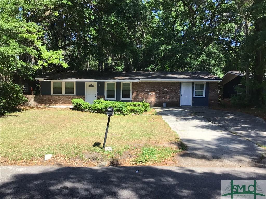 ranch-style home with brick siding, driveway, and a front yard
