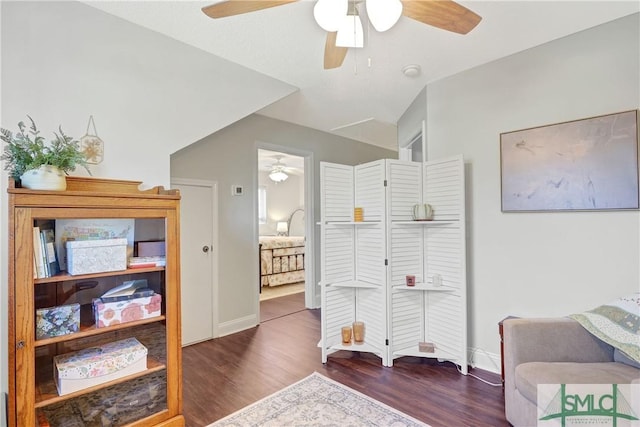 living area featuring baseboards, a ceiling fan, and wood finished floors