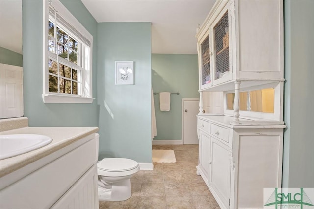 bathroom with toilet, baseboards, and vanity