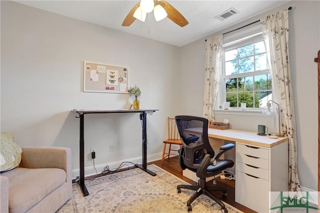home office featuring a ceiling fan, baseboards, visible vents, and wood finished floors