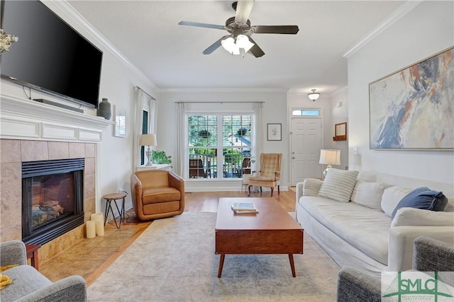 living area featuring ceiling fan, ornamental molding, wood finished floors, and a tile fireplace