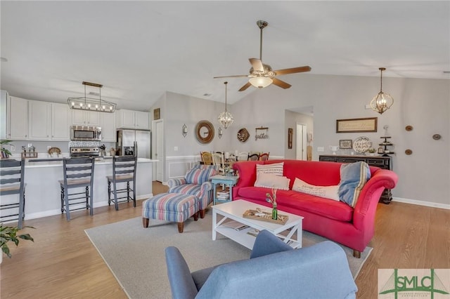 living room with baseboards, lofted ceiling, ceiling fan with notable chandelier, and light wood-type flooring