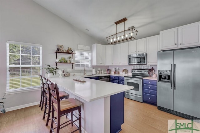 kitchen with a breakfast bar area, blue cabinetry, appliances with stainless steel finishes, a sink, and a peninsula