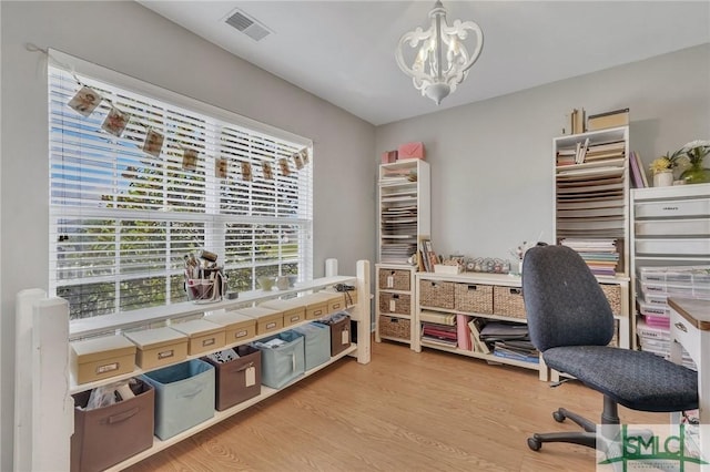 home office with an inviting chandelier, light wood finished floors, and visible vents
