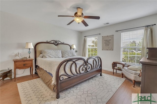 bedroom featuring a ceiling fan, baseboards, visible vents, and wood finished floors