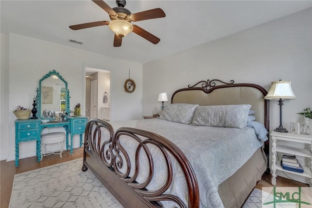 bedroom featuring a ceiling fan, visible vents, wood finished floors, and ensuite bathroom