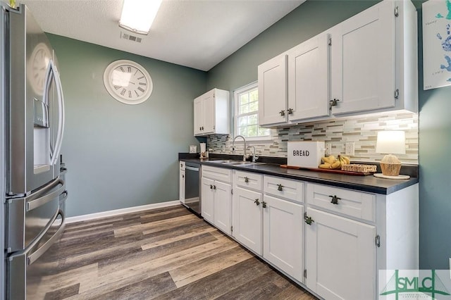 kitchen with a sink, appliances with stainless steel finishes, white cabinets, and dark countertops