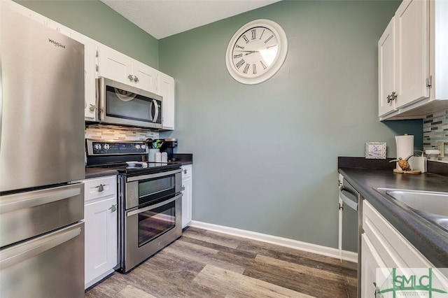kitchen with dark countertops, appliances with stainless steel finishes, decorative backsplash, and wood finished floors