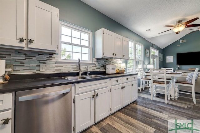 kitchen with ceiling fan, dark countertops, stainless steel dishwasher, vaulted ceiling, and a sink