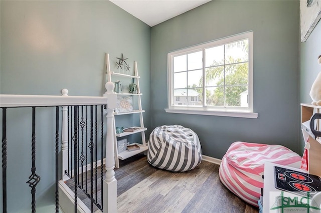interior space with baseboards, wood finished floors, and an upstairs landing