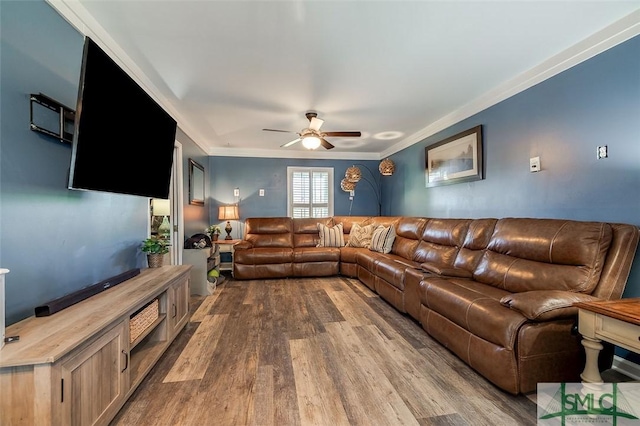 living room with crown molding, dark wood-style flooring, and ceiling fan