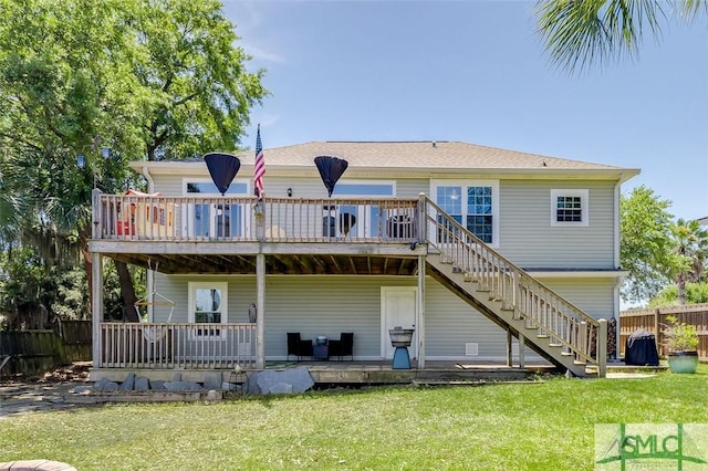 rear view of house with a lawn, fence, a wooden deck, and stairs